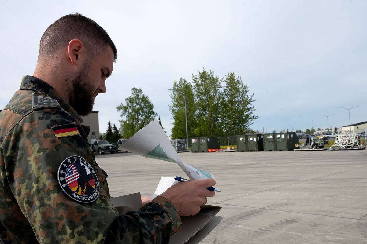 Pracovník kontroluje nákladní manifest vedle přepravních kontejnerů