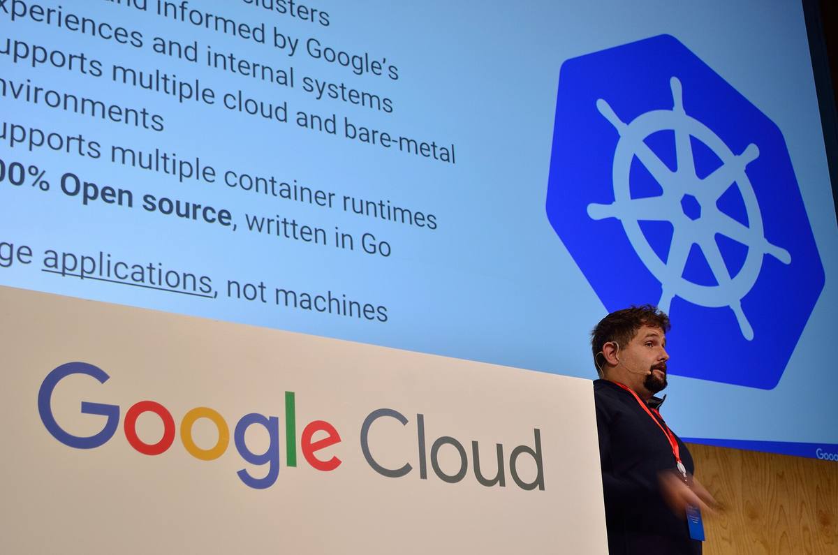 Přednášející před snímkem s logem Kubernetes na konferenci Google Cloud