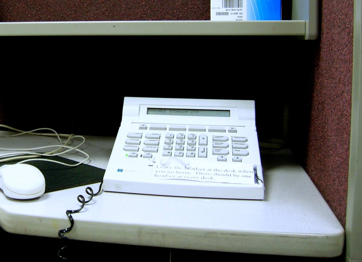 Telefonní přístroj se sluchátky na stole v call centru