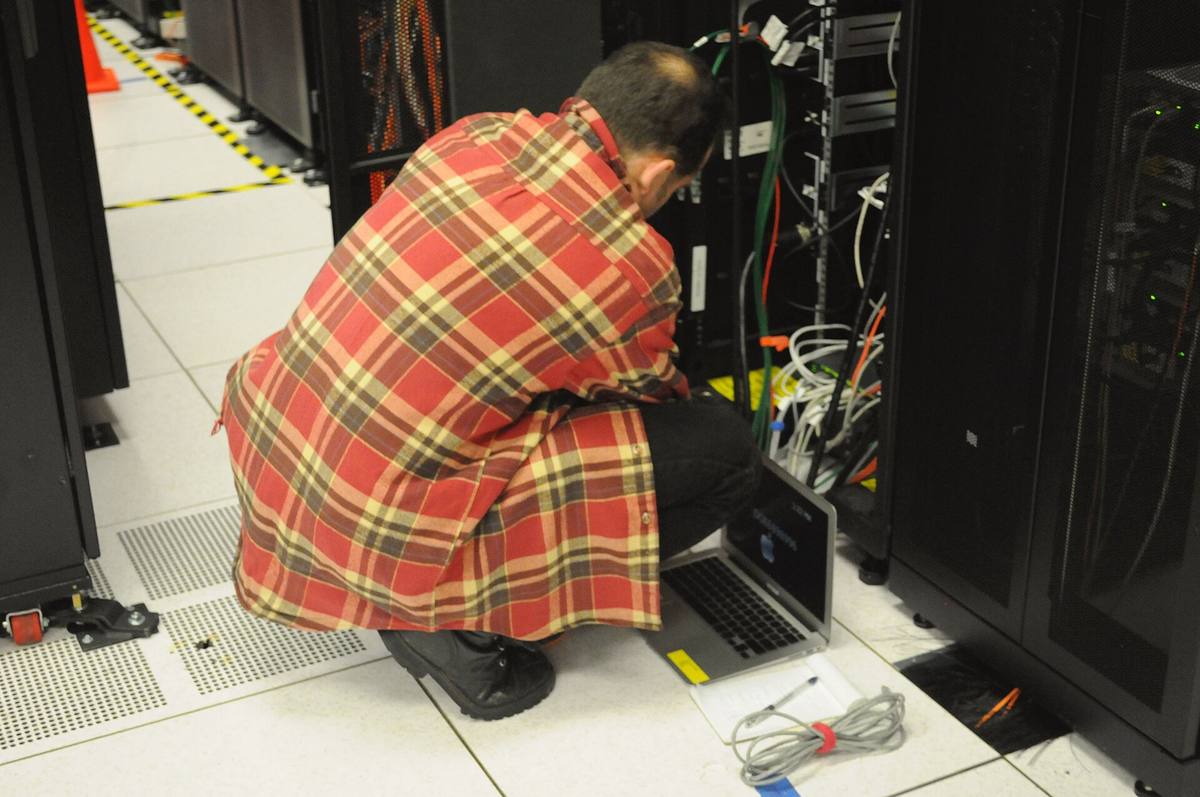 Technik s notebookem pracuje u otevřené serverové skříně